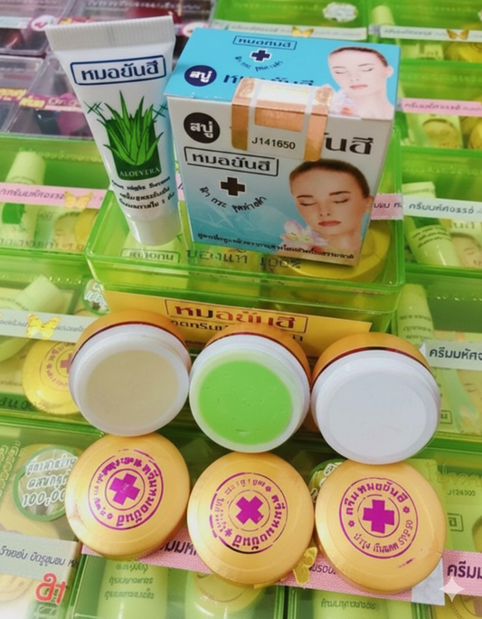 Assorted health and beauty products including aloe vera gel, cream, and small containers on a green background.